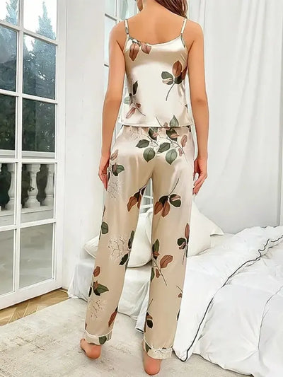 Back view of woman in champagne satin leaf print cami top and wide-leg pajama pants by window