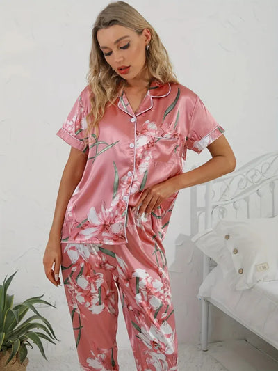 Woman in pink floral satin pajama set looking down, close-up front view of notched collar top