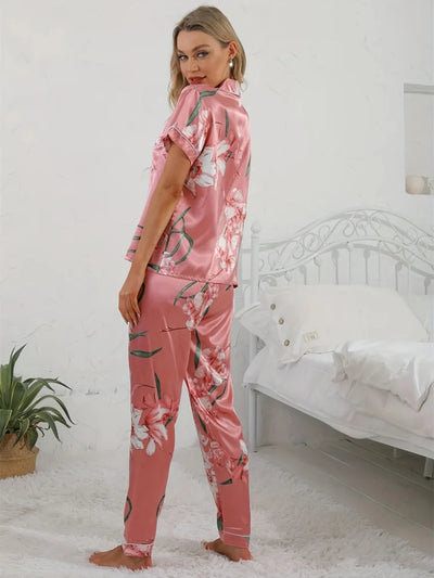 Back view of woman in pink lily-print satin pajama set showing full-length pants and top