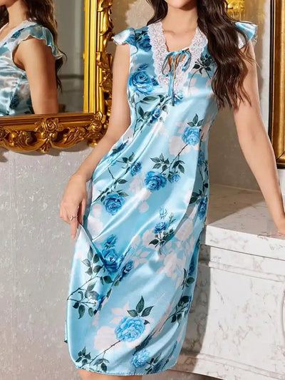 Woman in blue floral satin midi pajama dress standing near ornate gold mirror in elegant bathroom setting