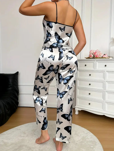 Back view of woman standing in white butterfly-print satin cami top and wide-leg pants