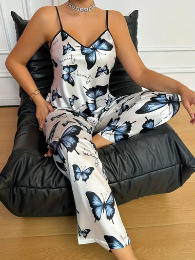 Woman seated on black leather chair in white butterfly satin cami pajama set