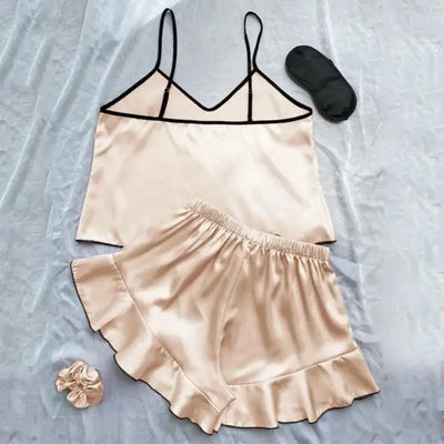 Champagne satin cami top and ruffle shorts set laid flat with sleep mask and matching scrunchie