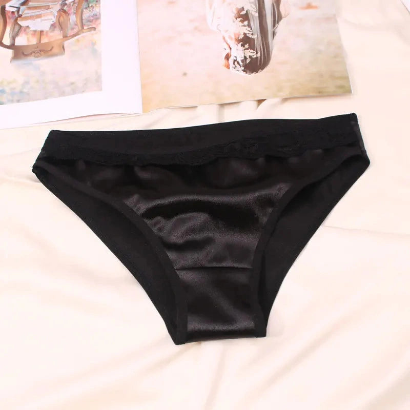 Black bikini satin panties with delicate lace waistband laid flat on bed