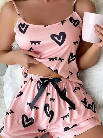 Overhead close-up of pink satin pajama set with heart print and ribbon tie waist