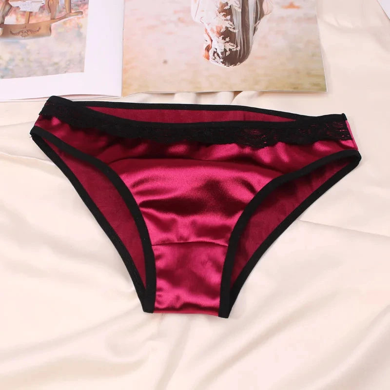 Wine red satin bikini panties with black lace waistband and black binding trim, flat lay on white fabric