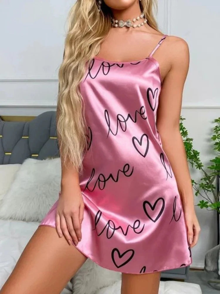 Front view of pink satin slip nightgown with black love and heart print, spaghetti straps, worn with pearl choker necklace
