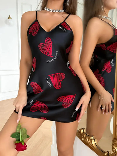 Front view of black heart print slip nightgown, model holding red rose near gold mirror