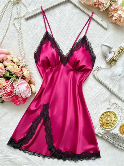 Hot pink satin mini nightgown with black lace trim flat lay on white surface with flowers and pearl necklace
