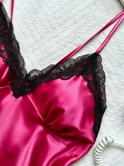 Close-up of deep V-neckline with wide black lace trim and double spaghetti straps on hot pink satin