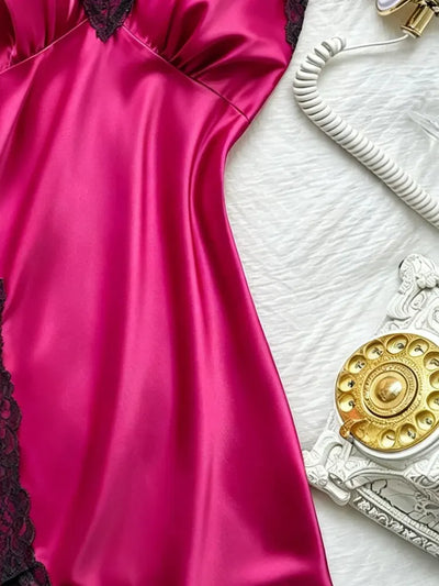 Side view of hot pink satin nightgown body showing high-shine finish next to vintage white telephone