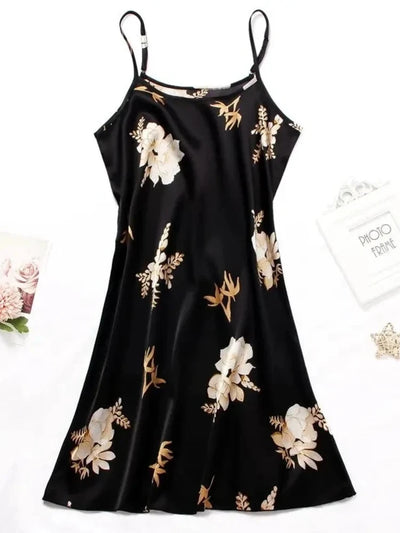 Flat lay of a black satin nightgown with white and gold floral print, adjustable straps, A-line shape