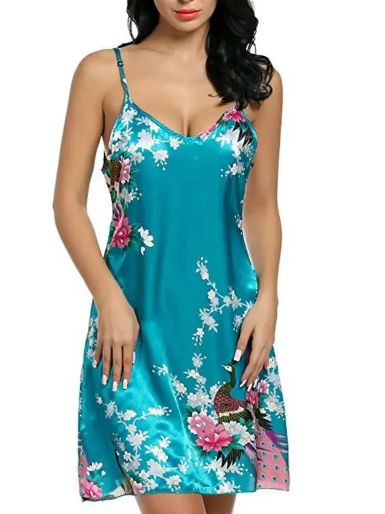 Teal satin mini nightgown with peacock floral print, deep V-neckline, and thin adjustable spaghetti straps, worn by a dark-haired woman against a white background