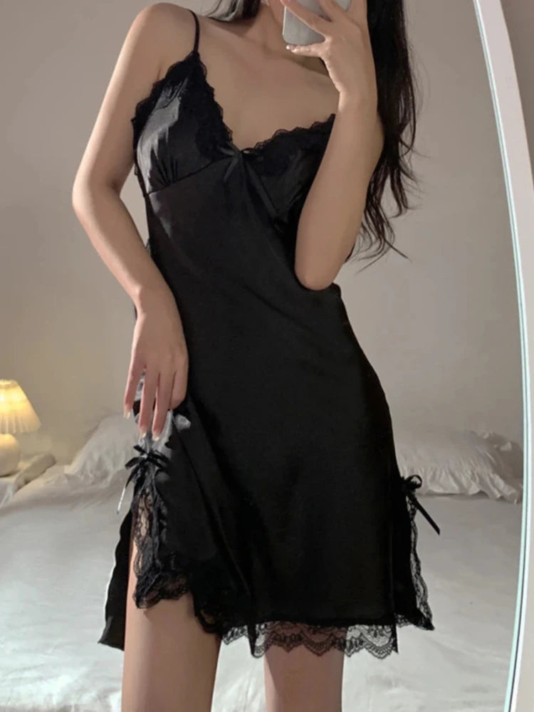 Woman wearing black satin mini nightgown with lace trim, bow detail, and side slits, mirror selfie