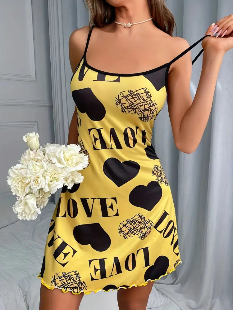 Front view of yellow satin nightgown with black love heart print and ruffled hem, model holding white flowers