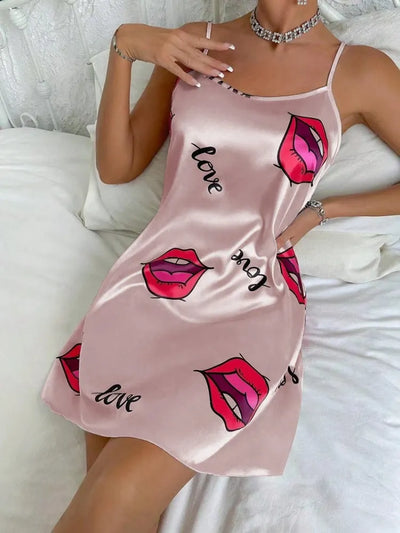 Blush pink satin mini nightgown with red lip print and love script worn in bed