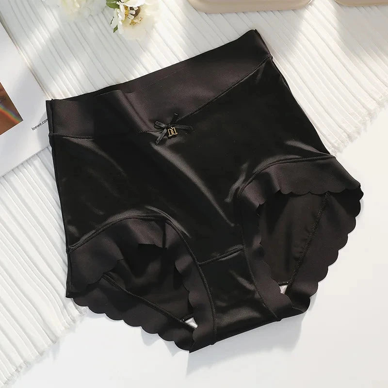 Black high-waist satin panties with scalloped hem and gold-tone bow accent, flat lay on white surface
