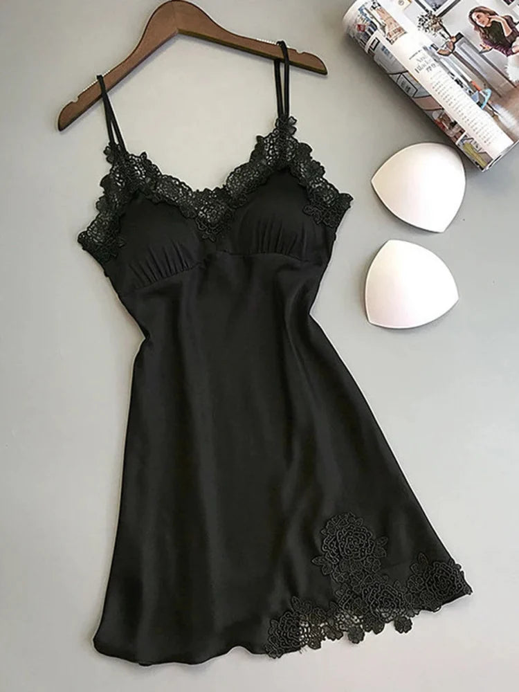 Black satin mini nightgown with lace V-neckline trim, spaghetti straps, and floral hem appliqué on wooden hanger