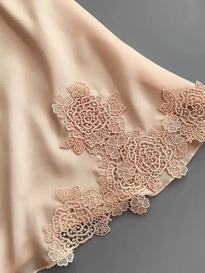 Close-up of champagne satin fabric with embroidered rose lace appliqué hem detail