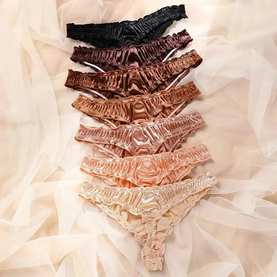 Overhead flat lay of satin ruffled thong panties ranging from black to pale champagne tones