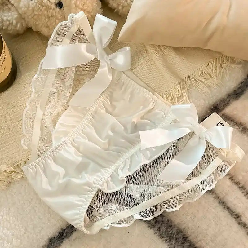 White tiered ruffle satin panties with mesh hem and ribbon bows on textured blanket