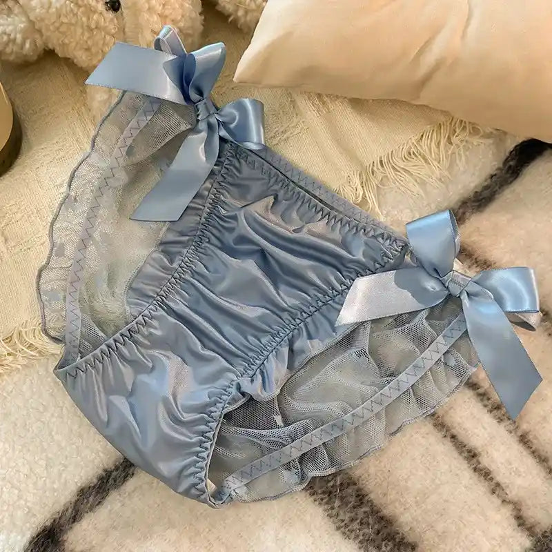 Blue satin and mesh bloomer panties with four ribbon bows laid flat on a cream blanket