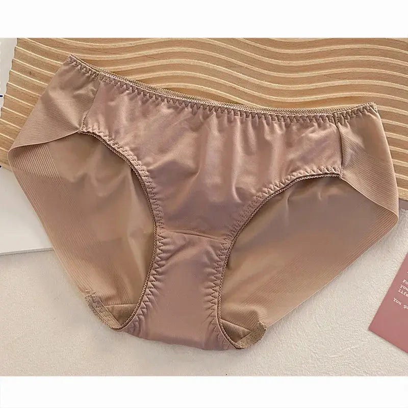 Nude satin bikini panties with gathered elastic waist laid flat on a striped surface
