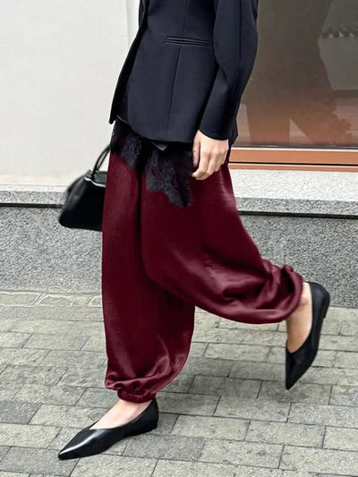 Burgundy wide-leg satin pants in motion, paired with black blazer and pointed flats